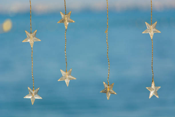Decorative bohemian LED light wires with stars hanging on bright blue beach and blurred background