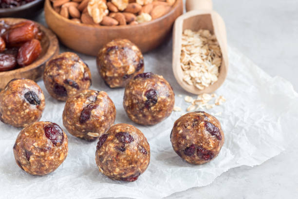 istock Healthy energy balls with cranberries, nuts, dates and rolled oats on parchment, horizontal, copy space 885973766