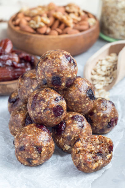 istock Healthy energy balls with cranberries, nuts, dates and rolled oats on parchment, vertical 885973788