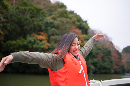 Young woman enjoying autumn foliage on tour boat
