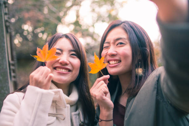 Happy sisters taking selfie picture with fallen leaves