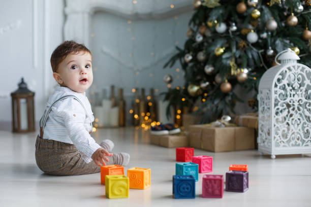 istock Cute little boy playing near the Christmas tree with colored cubes 886001064