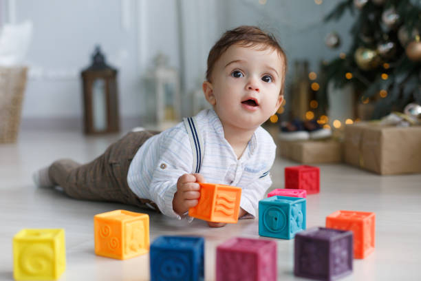 istock Cute little boy playing near the Christmas tree with colored cubes 886001066