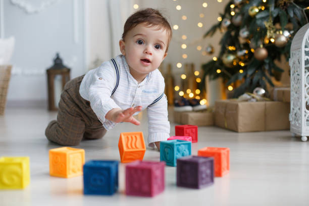 istock Cute little boy playing near the Christmas tree with colored cubes 886001068
