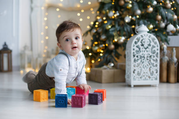 istock Cute little boy playing near the Christmas tree with colored cubes 886001074