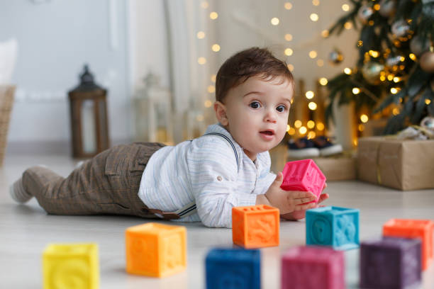 istock Cute little boy playing near the Christmas tree with colored cubes 886001076