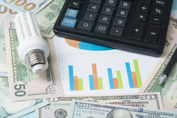istock Energy saving lamp , chart and calculator on money background Energy saving,saving electricity concept. 886013194