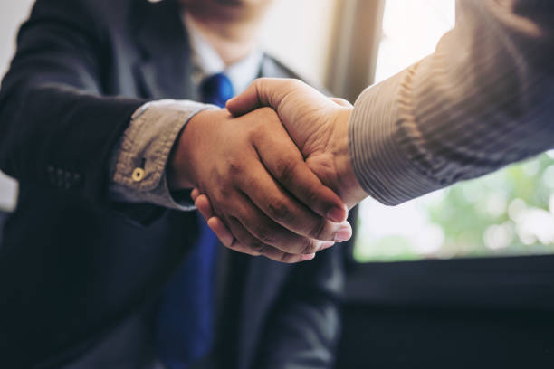 due uomini d'affari che si stringono la mano durante un incontro per firmare un accordo e diventare un partner commerciale, imprese, aziende, fiduciosi, affari di successo, contratto tra le loro aziende - hi technology foto e immagini stock
