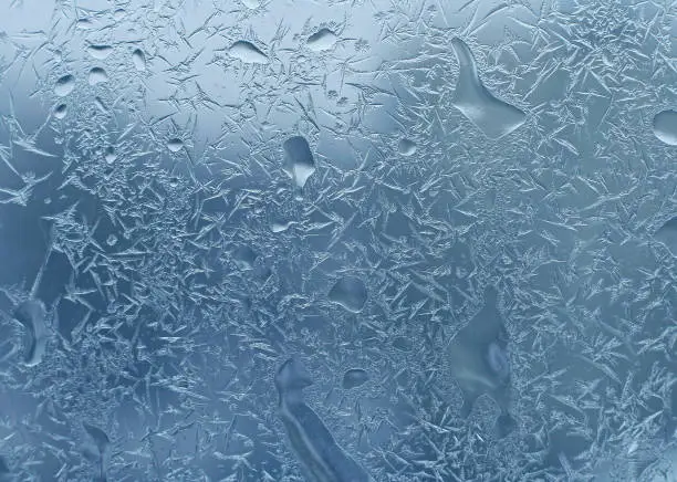 Abstract ice natural pattern and water drops on winter window glass, close-up background