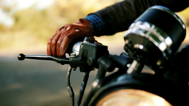 Closeup view of a man's hand in brown leather mitts starting the engine. Slowmotion shot