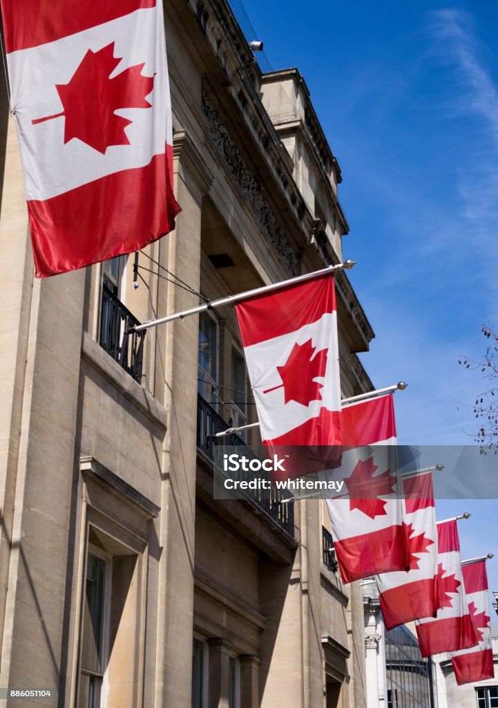 High Commission of Canada, London A row of Canadian flags on flagpoles outside the High Commission of Canada in Trafalgar Square, London, on a bright sunny day in early spring. Architecture Stock Photo