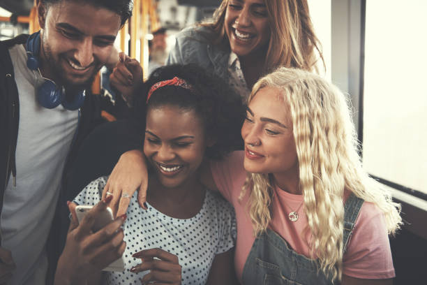 istock Young friends laughing and using a cellphone on the bus 886051836