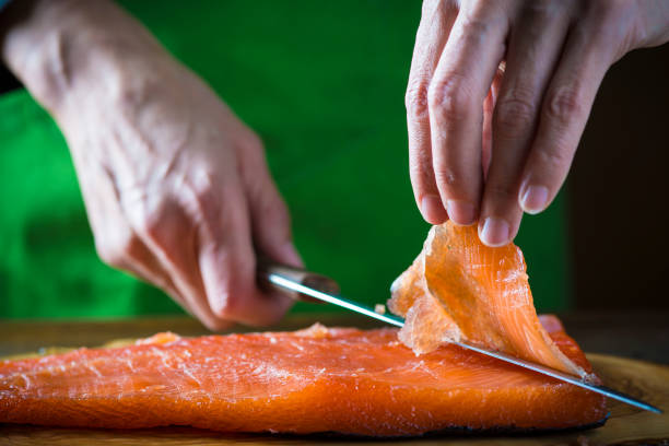 Slicing gravlax salmon with a knife stock photo