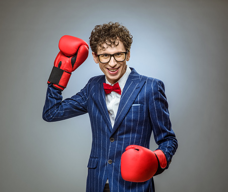 Businessman in boxing gloves smiling and ready to fight
