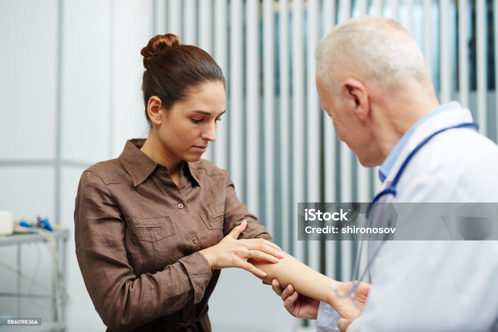 Pain in arm Young sick woman showing her arm to doctor while visiting clinics Skin Stock Photo