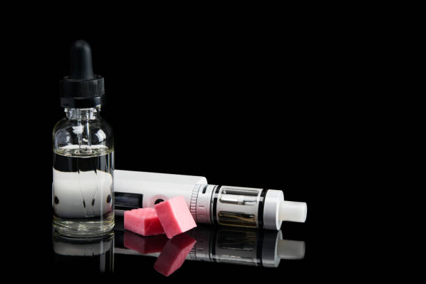 istock electronic cigarette and taste of candy in a bottle, concept on a black background with reflection 886106984