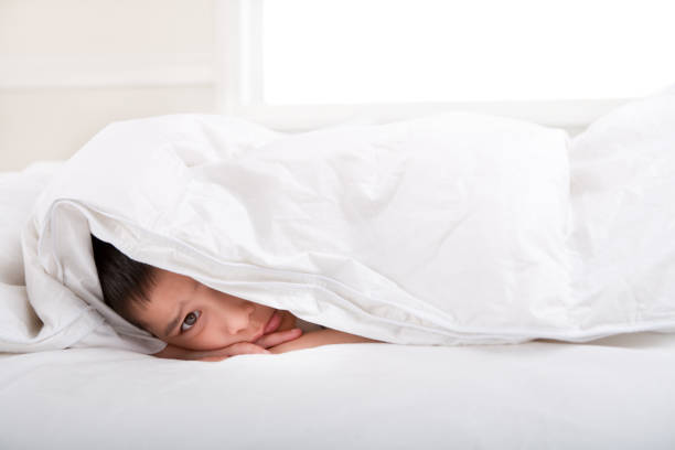 istock Sad little boy under duvet 886110384