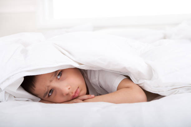 istock Sad little boy under duvet 886118068