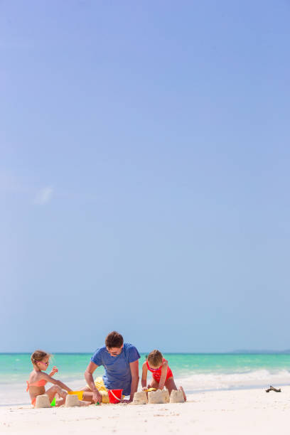 istock Father and kids making sand castle at tropical beach 886121400