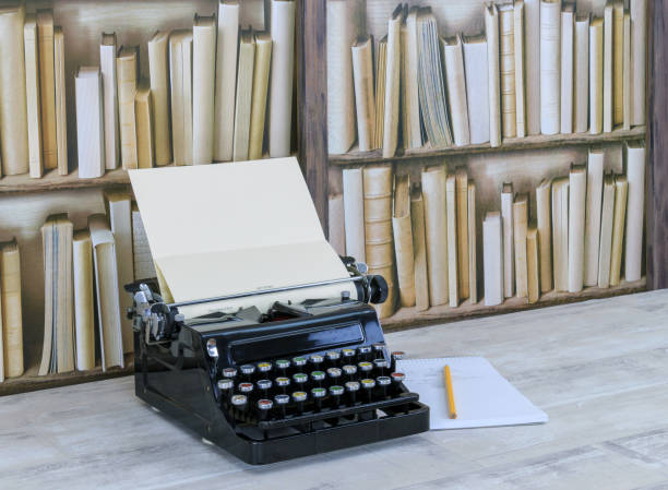 istock Vintage black typewriter, notepad and pencil on a desktop with old bookcase background 886121758