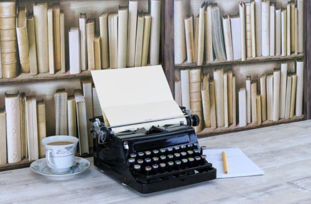 istock Vintage black typewriter, notepad, pencil and china teacup with tea on a desktop with old bookcase background 886121846
