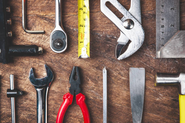 istock Top view of Working tools,wrench,socket wrench,hammer,screwdriver,plier,electric drill,tape measure,machinist square and safety glasses on wooden background.flat lay design for construction concept. 886122654