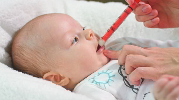 Baby Girl is Taking Medicine by a syringe Little baby girl is taking juice medicine helping by a syringe handled by mother child liquid medicine stock pictures, royalty-free photos & images