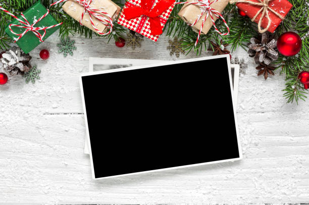 istock christmas blank photo frames with fir tree branches, decorations and gift boxes over white wooden background 886156112