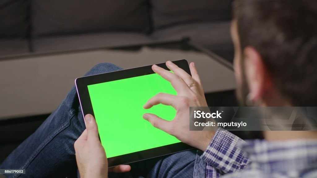 Green Screen Digital Tablet PC Man Young man using digital tablet pc with blue screen sitting at home. zoom Digital Tablet Stock Photo