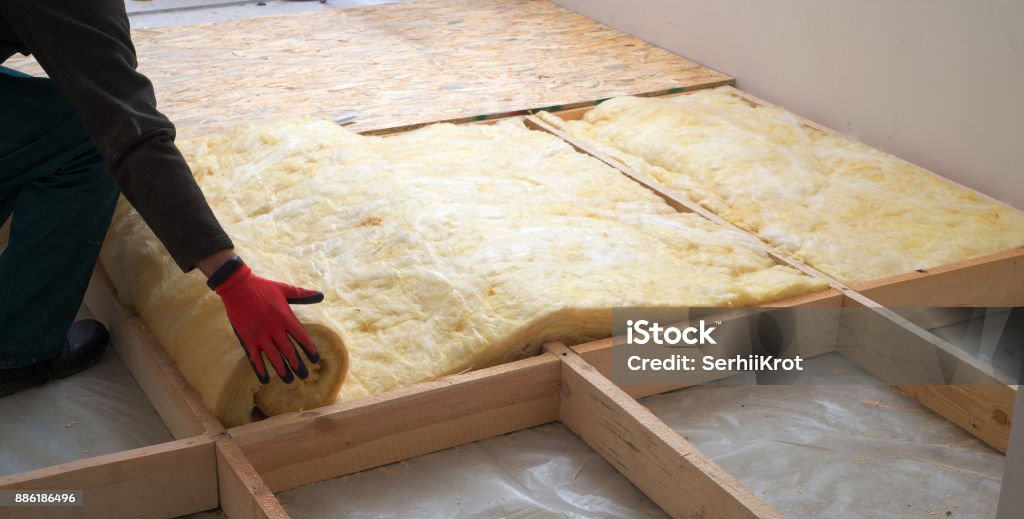 Work composed of mineral wool insulation in the floor, floor heating insulation , warm house, eco-friendly insulation, a builder at work Insulation Stock Photo