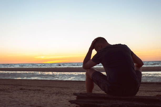 istock Burdened by unseen worries. Sad lonely man sits on beach 886193230