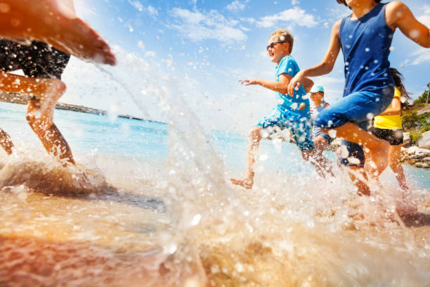 niños que se divierten corren hacer salpicaduras en aguas poco profundas - early teens child swimming pool swimming fotografías e imágenes de stock