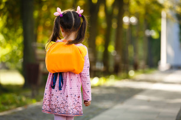 A schoolgirl girl with a briefcase on her back goes to school. Back to school.