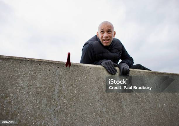 Burglar With Crowbar Climbing Over Wall Stock Photo - Download Image Now - Climbing, Surrounding Wall, Anxiety