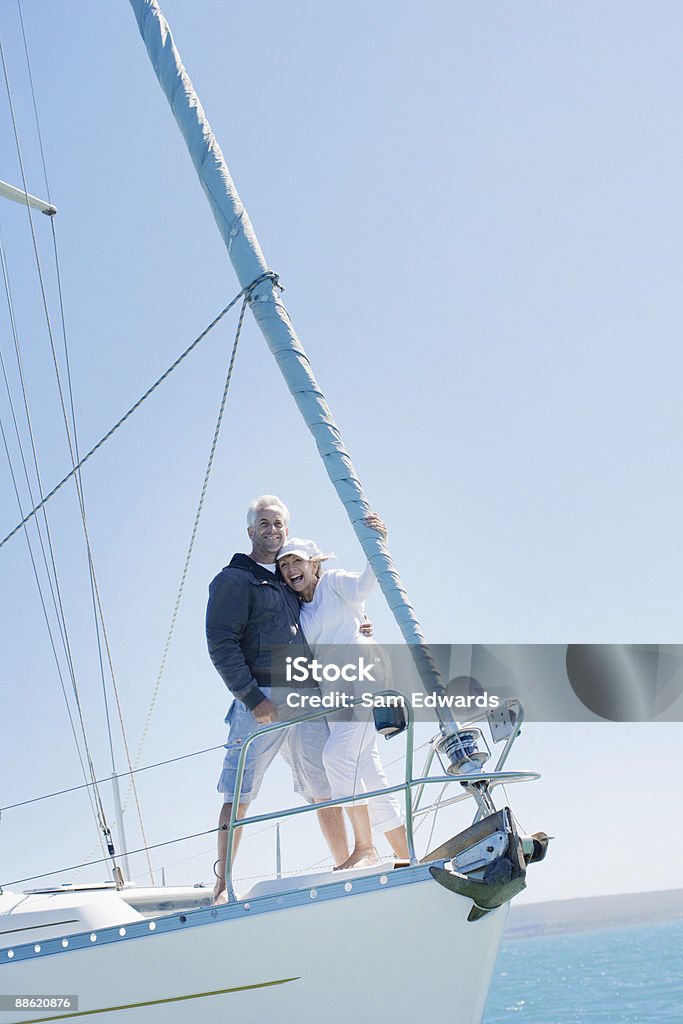 Coppia matura abbracciare sul ponte della barca a vela - Foto stock royalty-free di Barca a vela