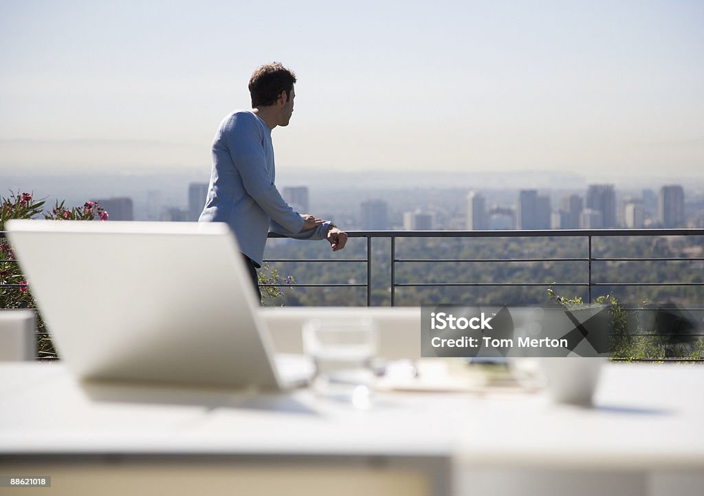 Man using laptop on balcony overlooking city  Luxury Stock Photo