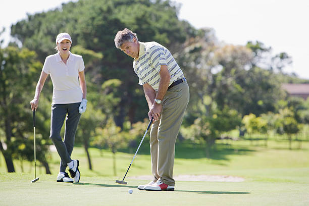 mature couple jouant au golf ensemble - golf playing men ball photos et images de collection