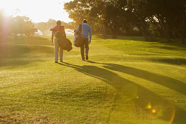 masculino llevando bolsas de golf en el campo de golf - golf course fotografías e imágenes de stock