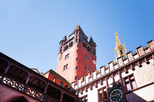 Low-angle view of Basel town hall tower and golden steeple against blue sky, Switzerland