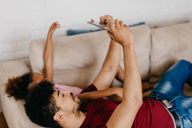 istock Father and daughter taking selfie while lying on the sofa 886230138