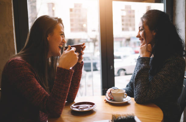 istock Two girls sitting in a cafe. Speaking to each other and having fun. 886237430