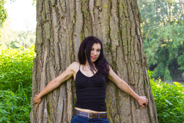 Young Woman Standing By A Large Tree In A Park