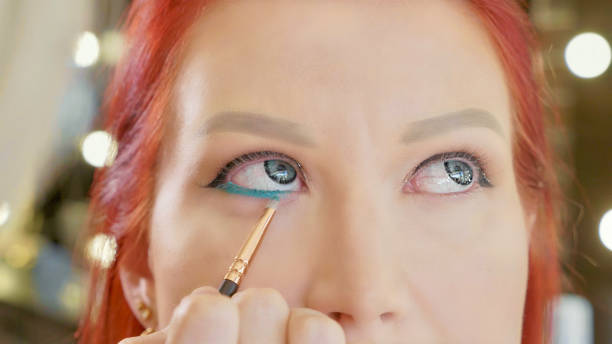 Make-up artist applying makeup to model's eye. Close up view.