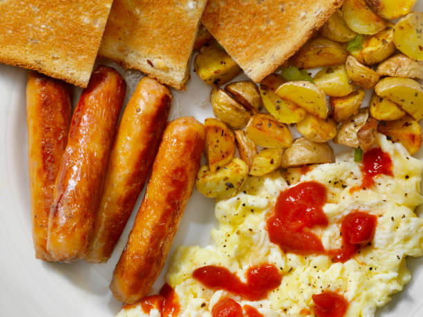 A plate of food for breakfast consisting of two hash browns, scrambled egg, chorizo, and lightly toasted white turkish bread