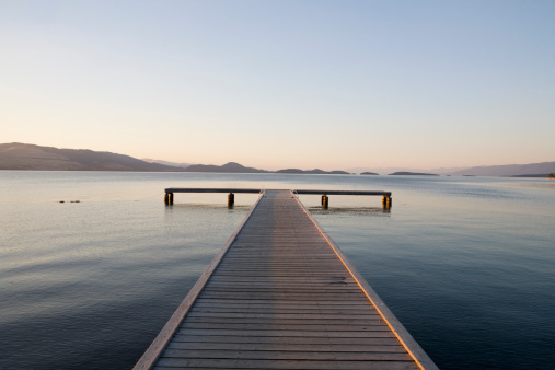 Scenic view of a dock with sunset approaching and mountains in the distance.