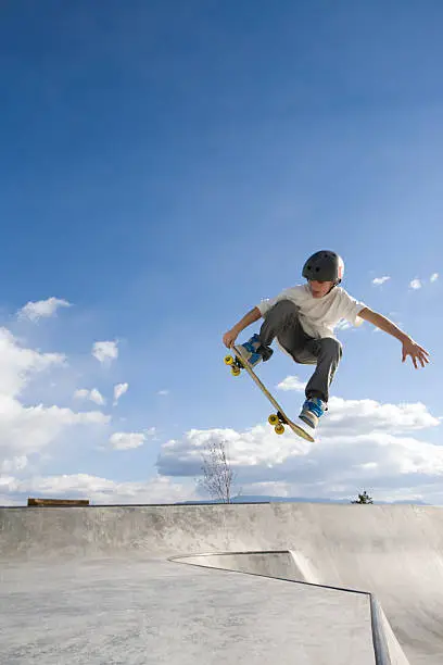 A young male on a skateboard catches some air in a skate park.