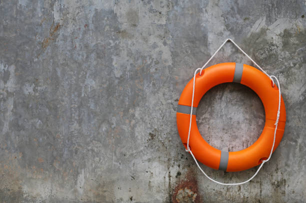 istock Orange Lifebuoy hanging on abstract cement wall Background. 886278384