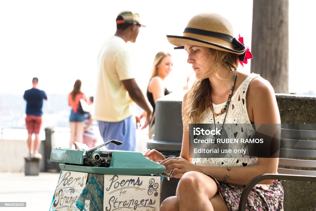 Poems for strangers at Pike Market, Seattle. Seattle, Washington: A young woman is writing poems for customers with a typewriter in the street at the waterfront of Seattle close to the Pike Market. Adult Stock Photo