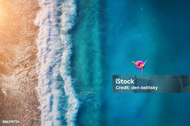 Aerial View Of Young Woman Swimming On The Pink Swim Ring In The Transparent Turquoise Sea In Oludeniz Summer Seascape With Girl Beach Beautiful Waves Blue Water At Sunset Top View From Drone Stock Photo - Download Image Now