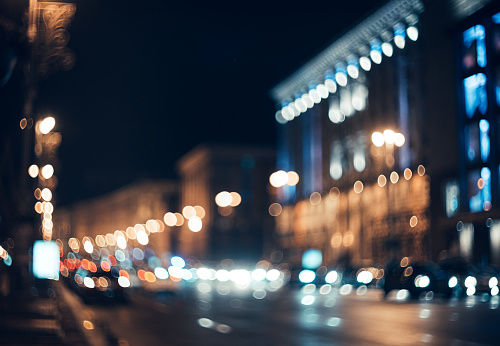 Blurred city at night. Bokeh. Beautiful abstract background with defocused buildings, cars, city lights, people. Colorful bokeh background with urban night scene. Design. Concept backdrop. Vintage